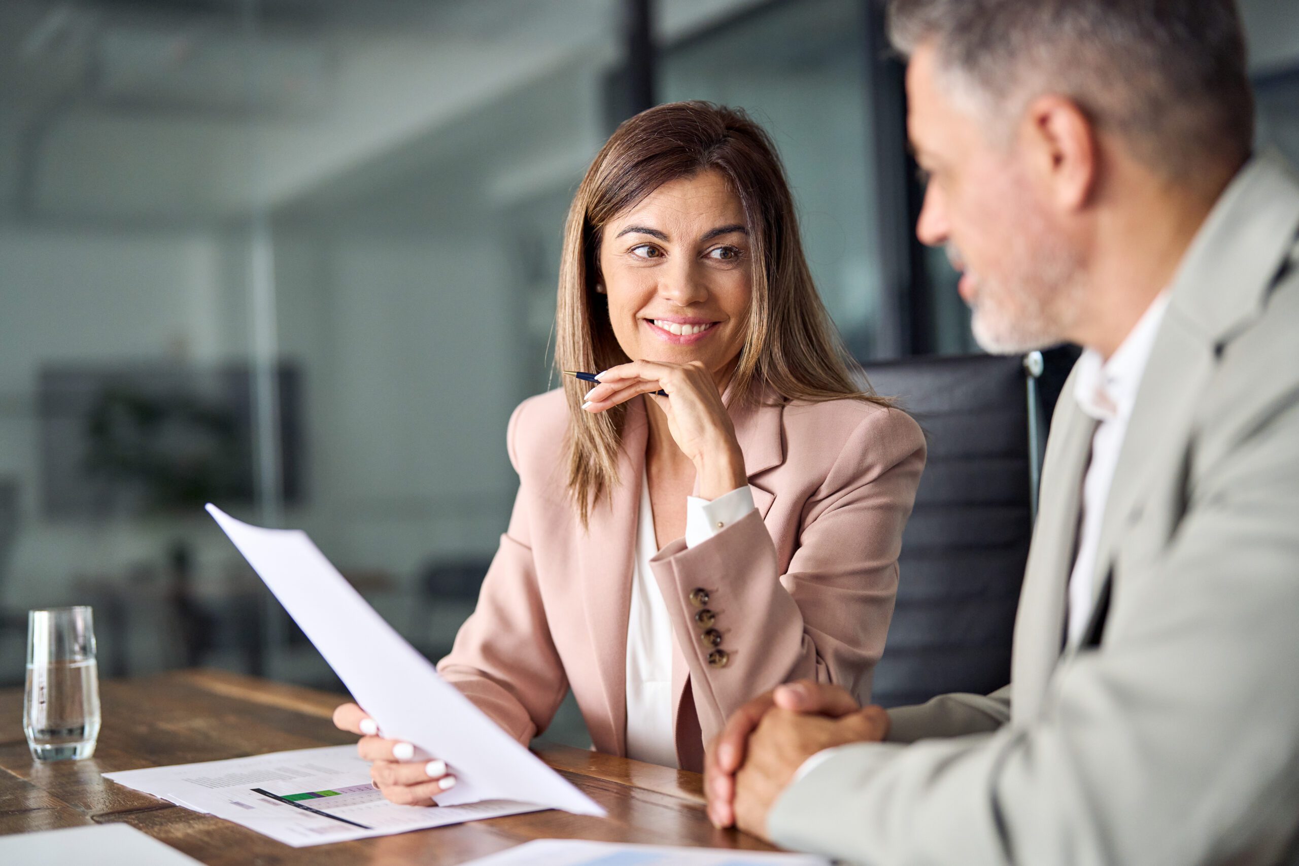 Two business executives discussing financial papers in office at meeting.