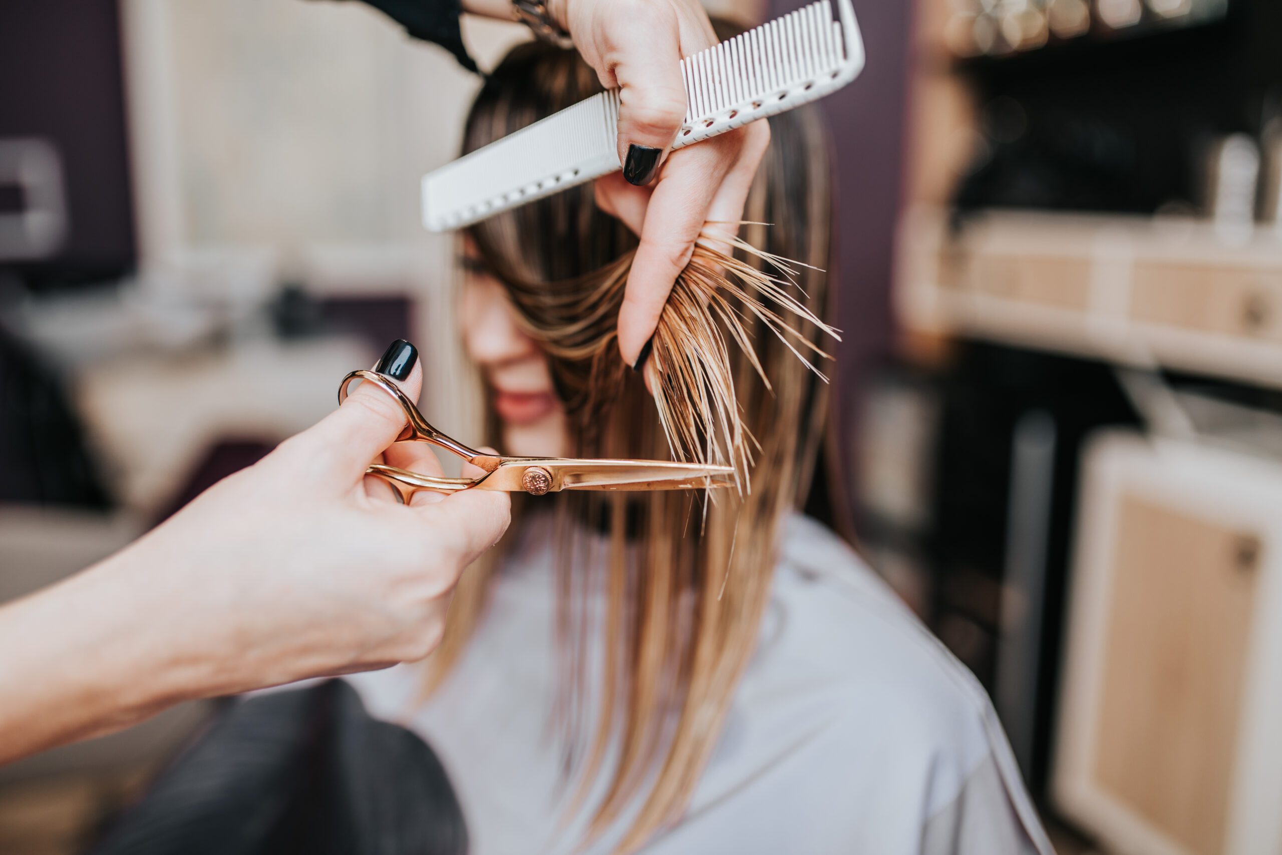 Beautiful young woman getting her haircut by a hairstylist at a