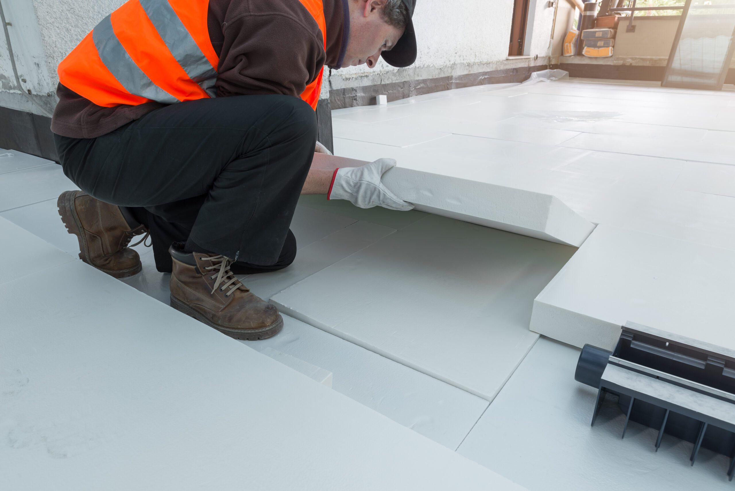 Professional worker is laying styrofoam insulation sheets on house terrace with roof function for thermal protection. Concept of energy efficiency. Waterproofing and thermal insulation