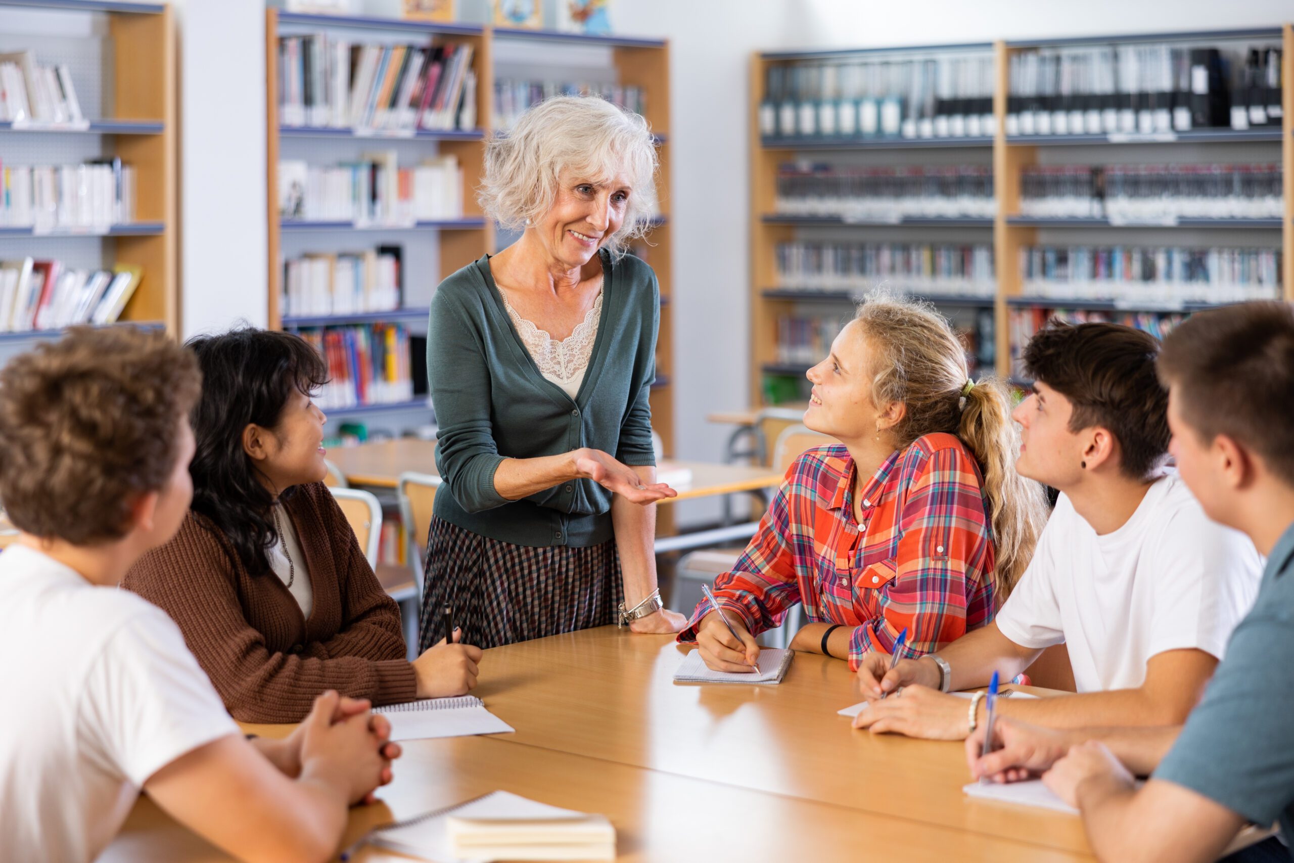Brainstorming teenagers students and elderly teacher at library